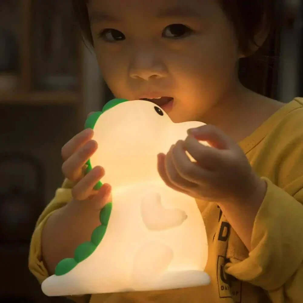 Child holding a Lovely Dinosaur Night Light with a soft glow.