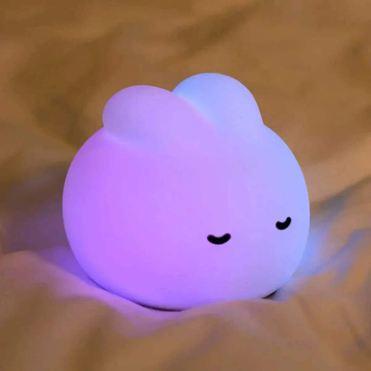 Soft glowing Baby Bunny Night Light on bed, BPA-free silicone, USB rechargeable, soothing for kids' rooms.