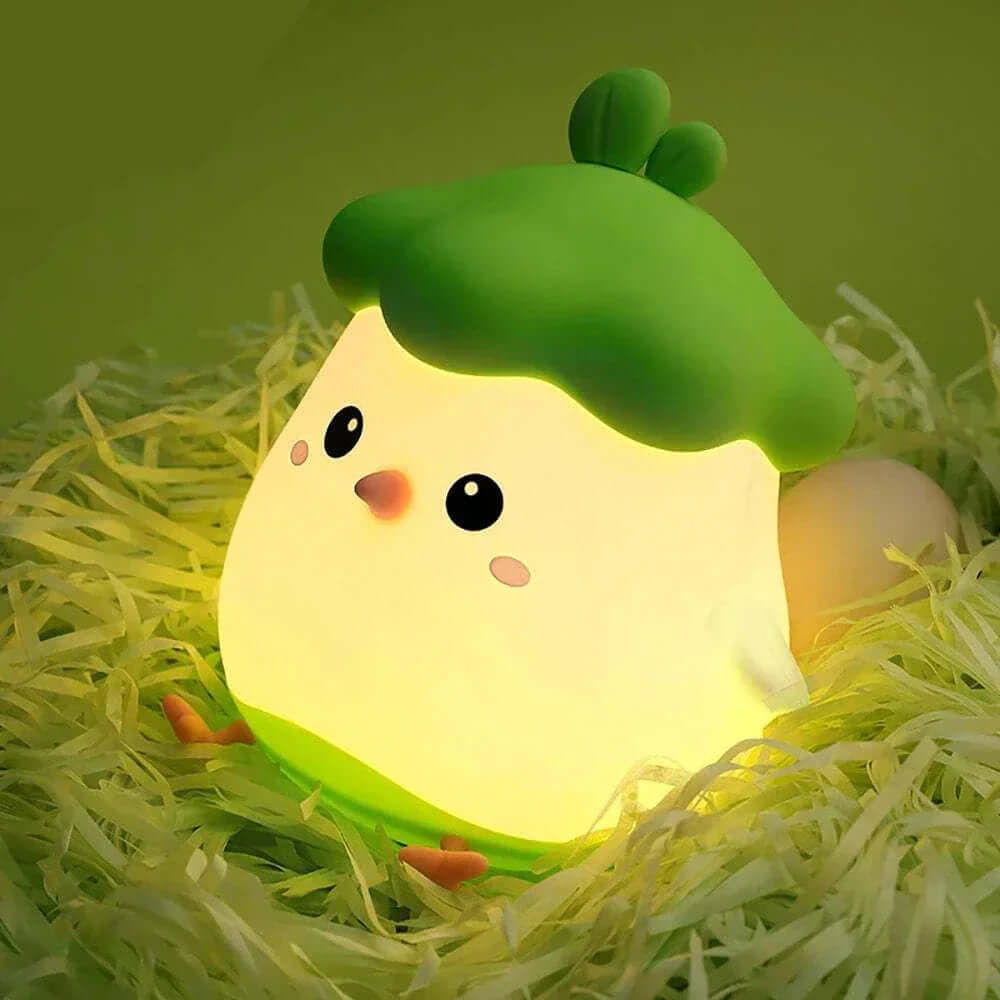 Adorable chick-shaped Veggie Chick Night Light with soft LED glow on green bedding.